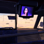 A player character sits in a vehicle, view of a desert road ahead and a TV screen showing a woman.