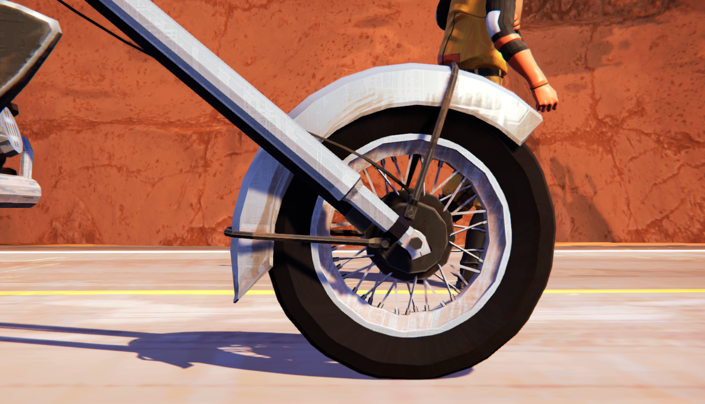 Close-up of a motorcycle wheel on a road with a desert backdrop.