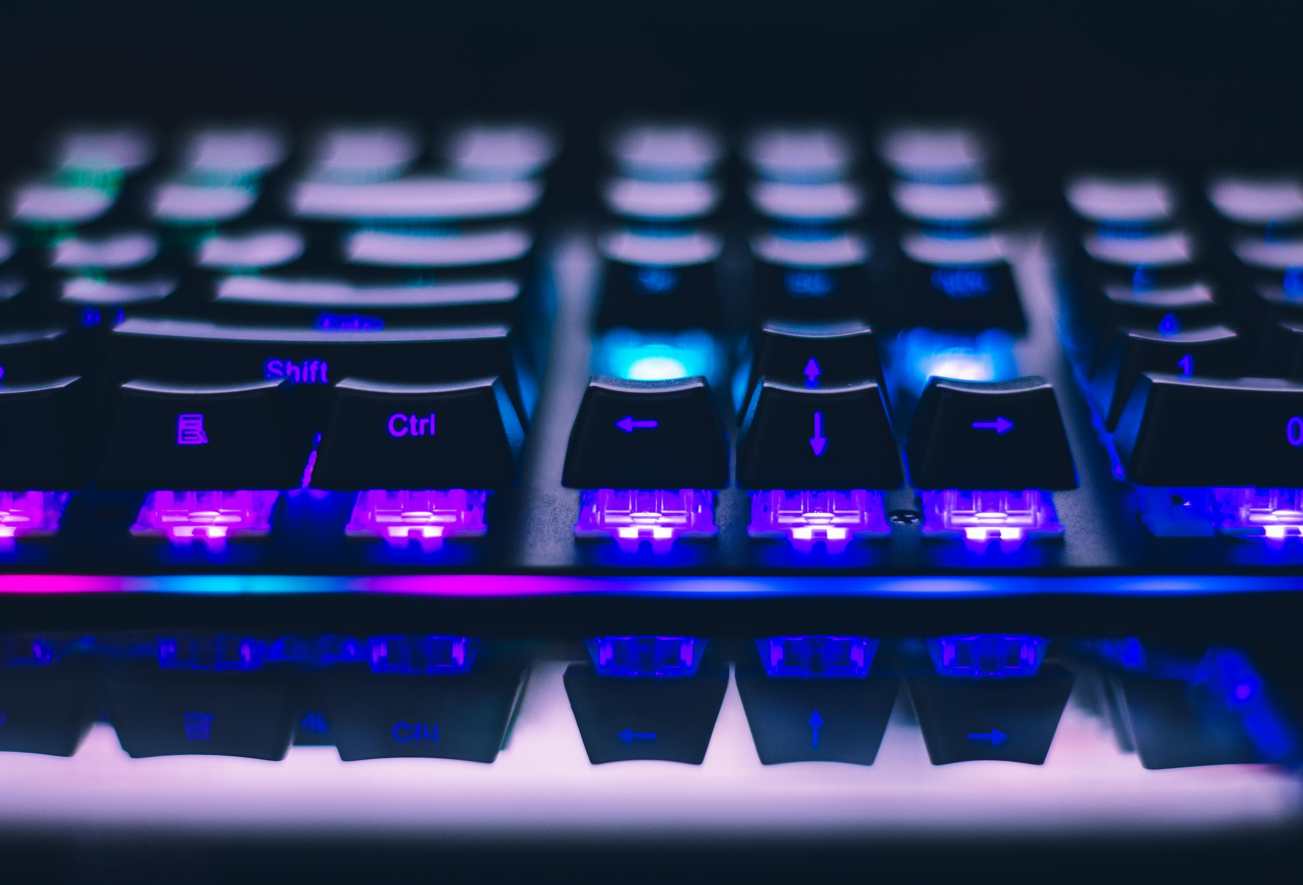 A detailed close-up of illuminated mechanical keyboard keys with focus on blue and purple lights