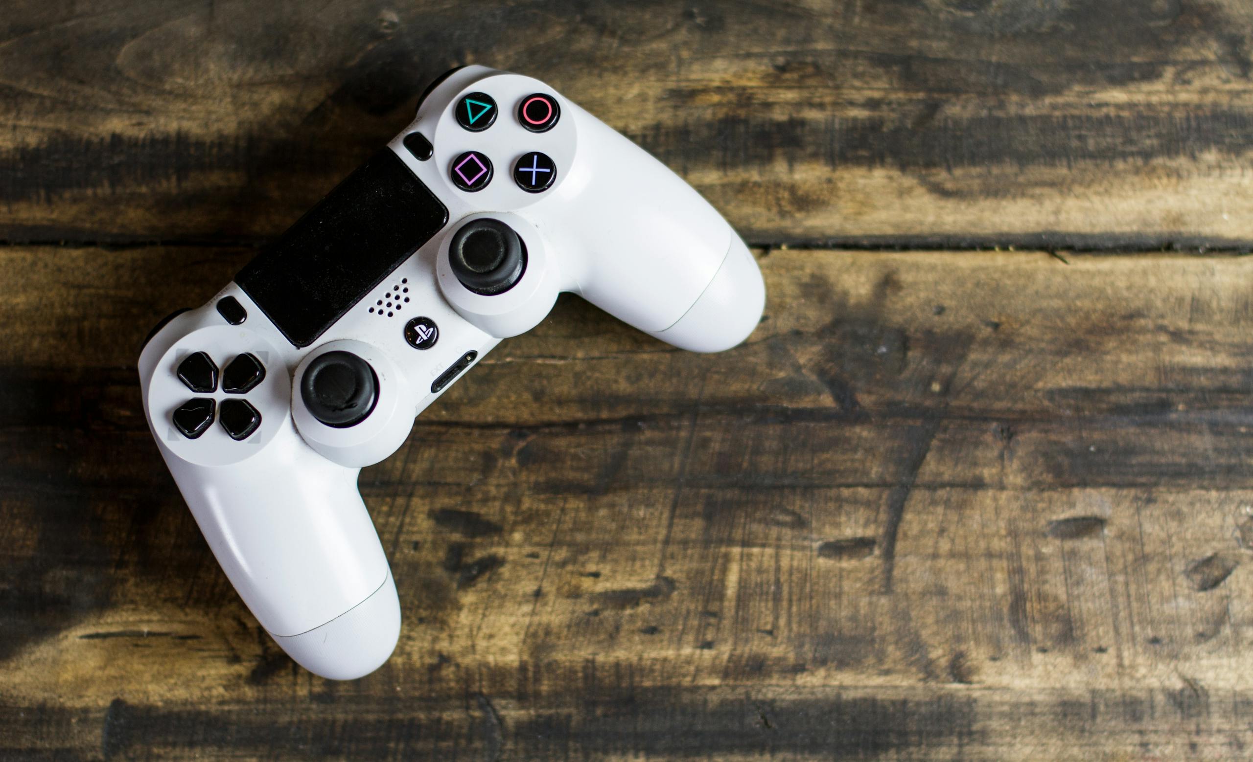 White game controller resting on a rustic wooden surface top view